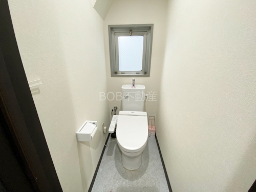 温水洗浄便座と窓、白い内装が映るトイレ内の画像