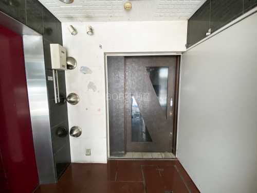 白壁と茶色のドア、エレベーターが映る画像